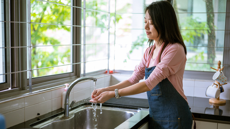 woman washing hands at kitchen sink