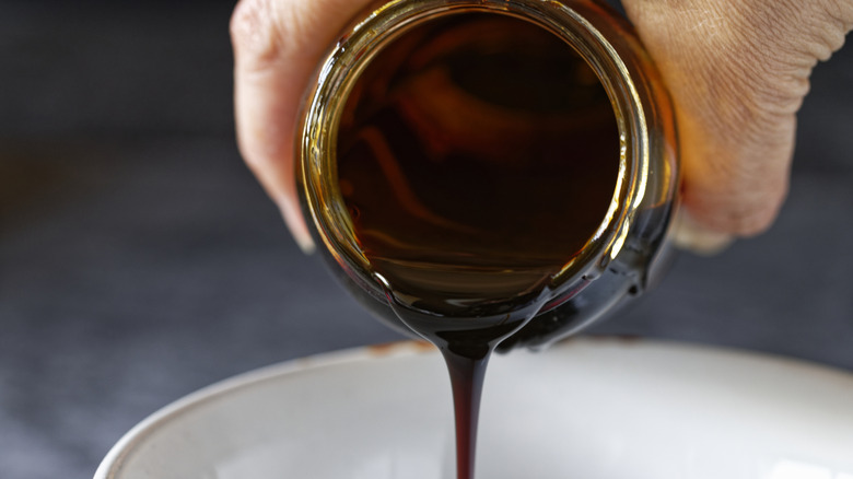 A hand pouring molasses into a bowl