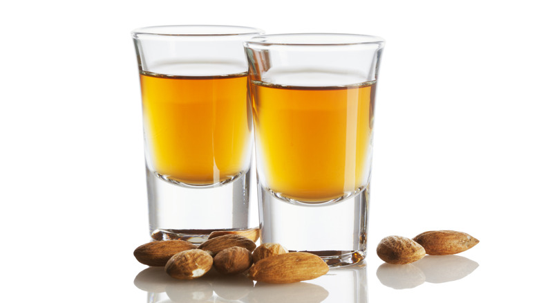 Two shot glasses of amaretto liqueur surrounded by whole almonds