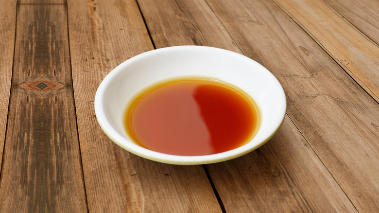 Small white bowl of fish sauce on wooden countertop