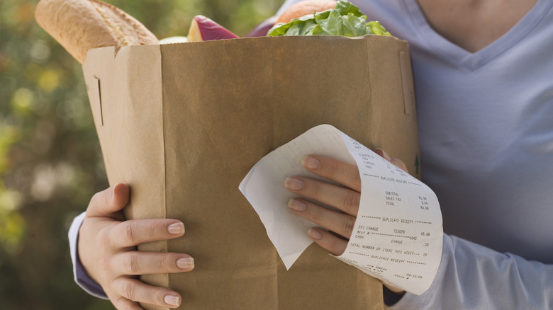 woman holding receipt and groceries