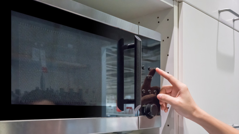 hand pressing buttons on microwave