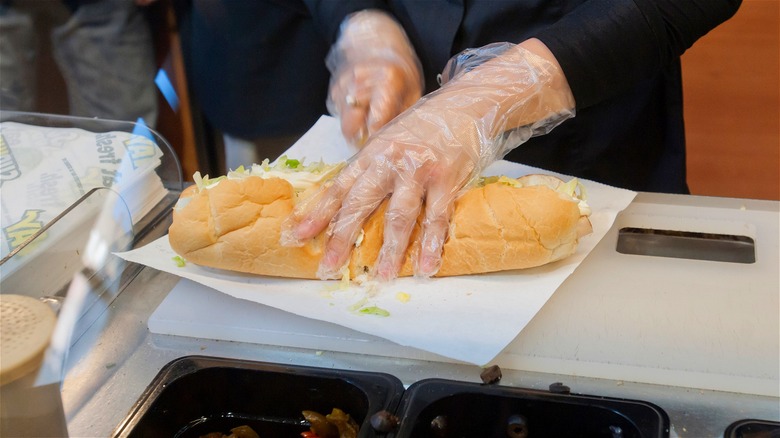 employee cutting footlong sub sandwich