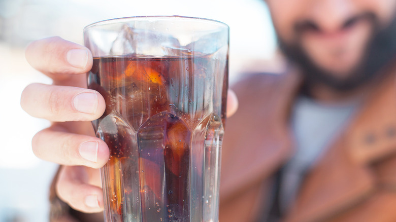 man holding coke glass