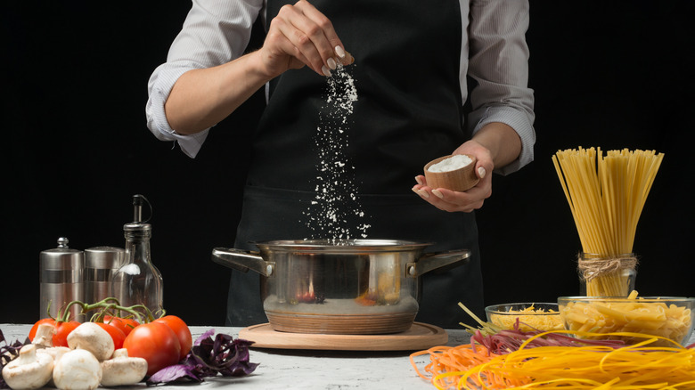 person salting water in pot