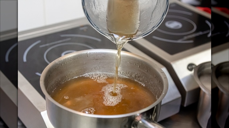 pouring chicken broth into pot