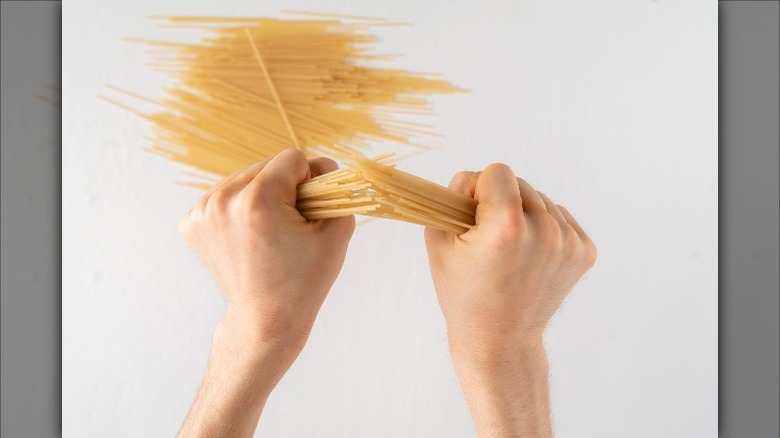 hands breaking dry spaghetti