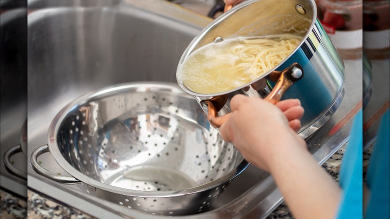 pouring pasta water into colander