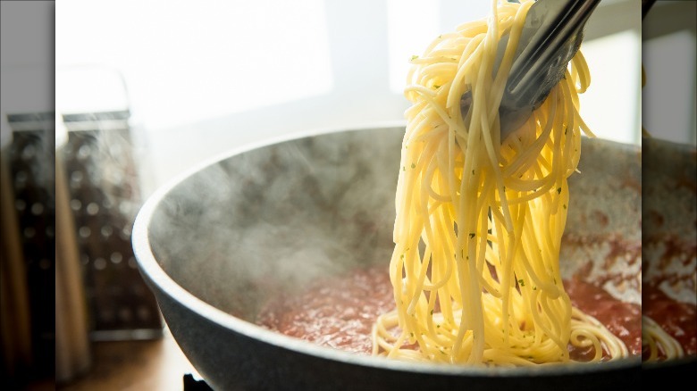 adding spaghetti to sauce