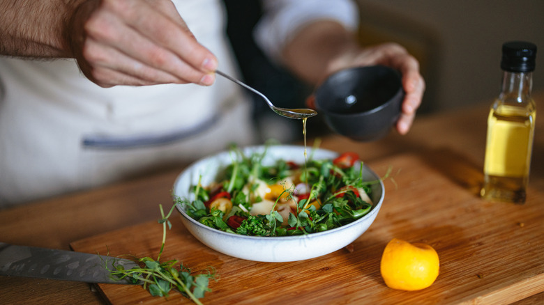 drizzling dressing on salad bowl