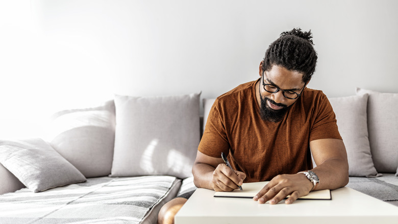 man writing in journal