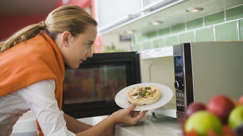 woman putting food in microwave