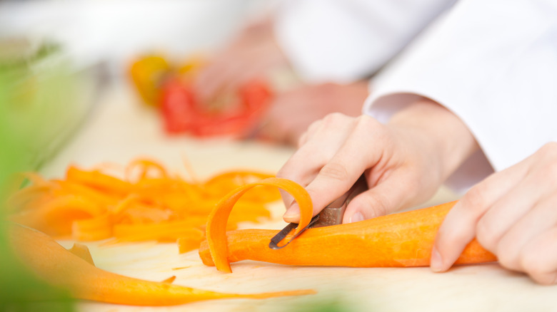 person peeling a carrot