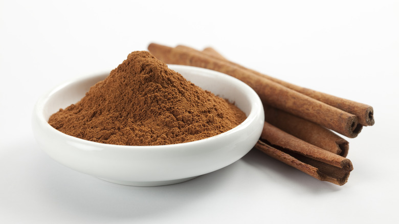 ground cinnamon in bowl with sticks