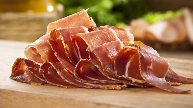 sliced prosciutto on wooden cutting board