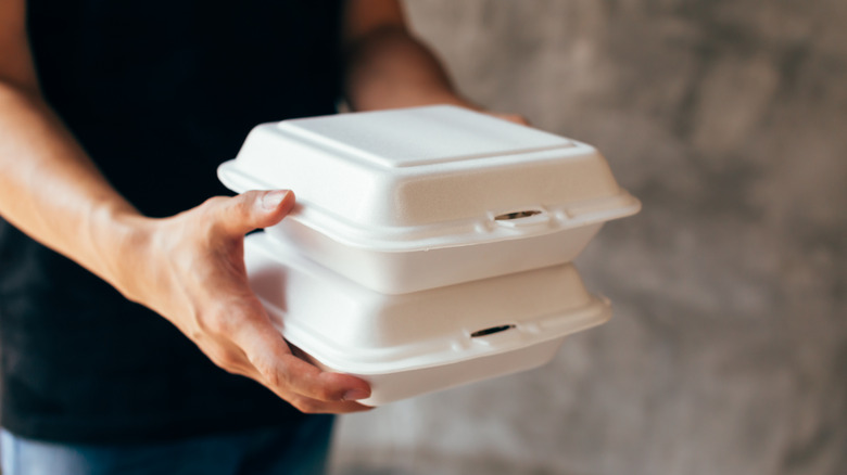 person holding to go containers