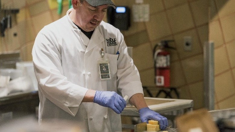 Whole Foods employee cutting cheese