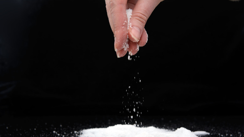 Hands dropping grains of salt