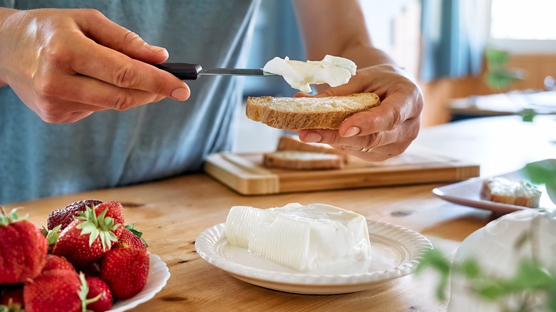 Spreading cream cheese on toast