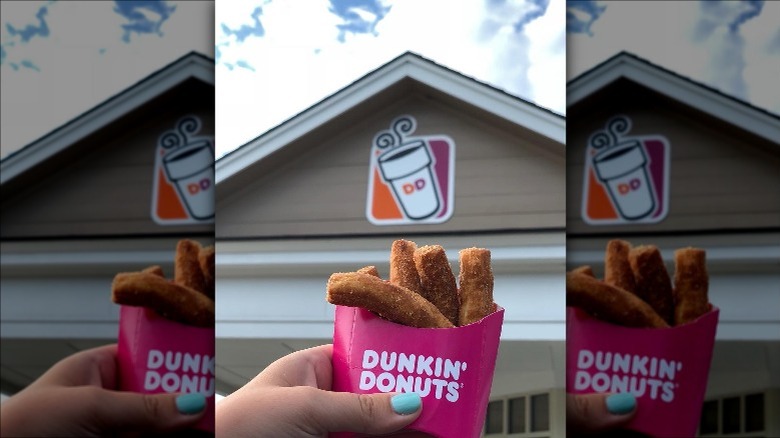 holding container of donut fries in front of Dunkin