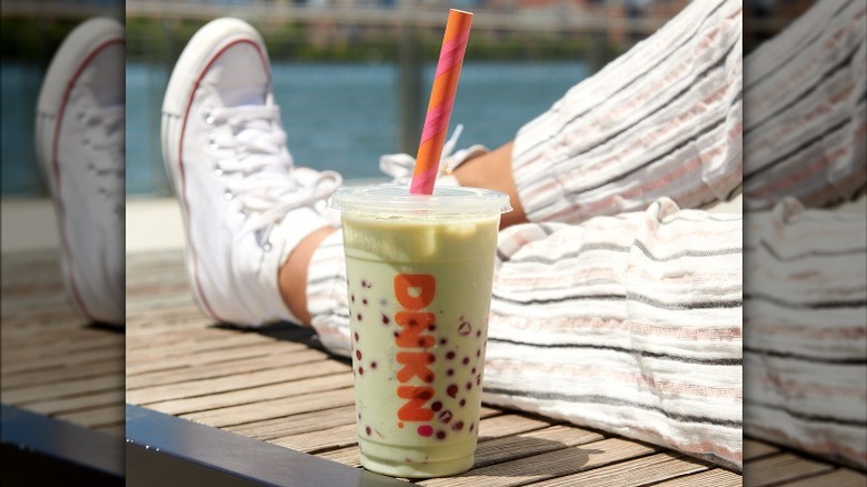 sitting with green and pink dotted drink 