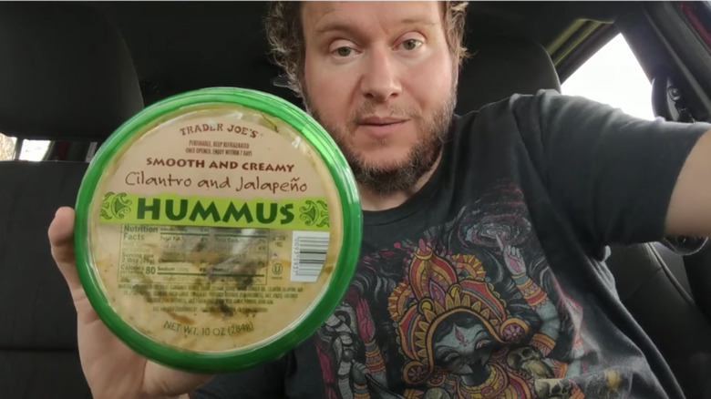 Man holding Trader Joe's Cilantro and Jalapeño Hummus