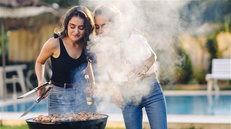 two people standing at grill