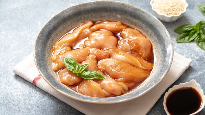 raw chicken marinating in bowl