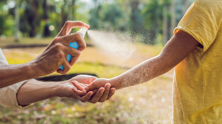 spraying sunscreen on arm