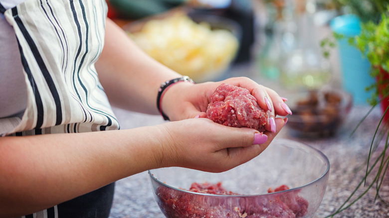 hands holding raw ground meat