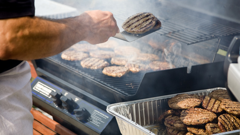 flipping hamburgers over grill