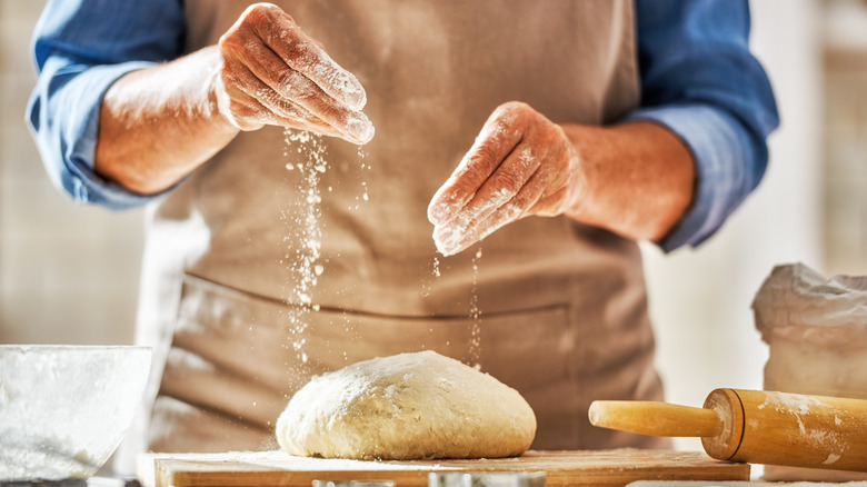 artisan making bread sprinkling flour