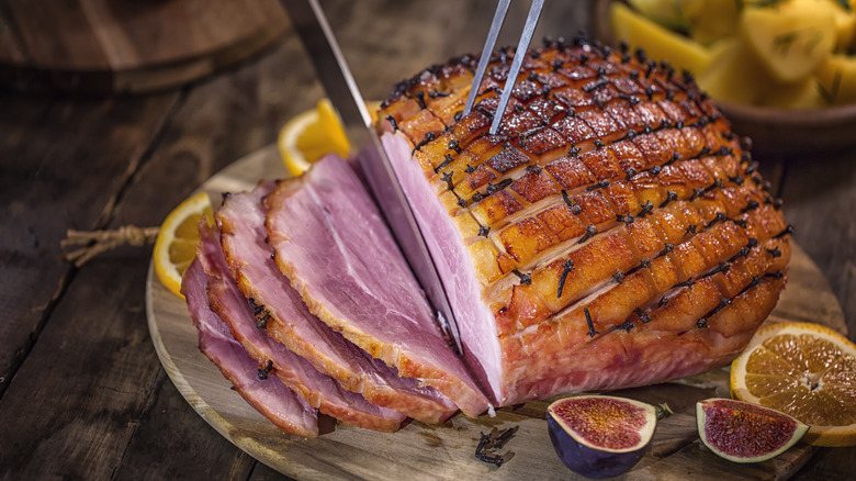 Person slicing glazed holiday ham