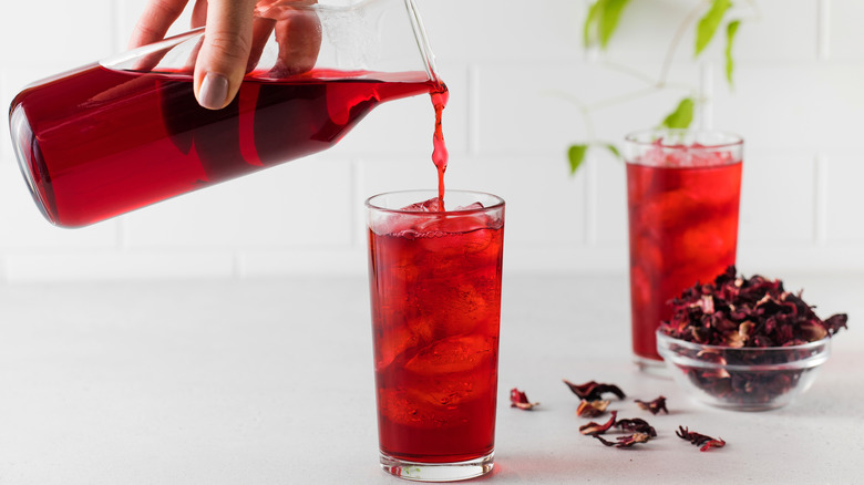 hand pouring hibiscus iced tea