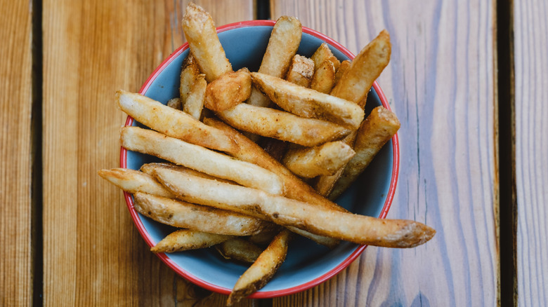 A bowl of french fries on a brown table