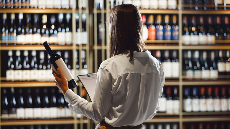 A wine expert checking the condition of a wine bottle