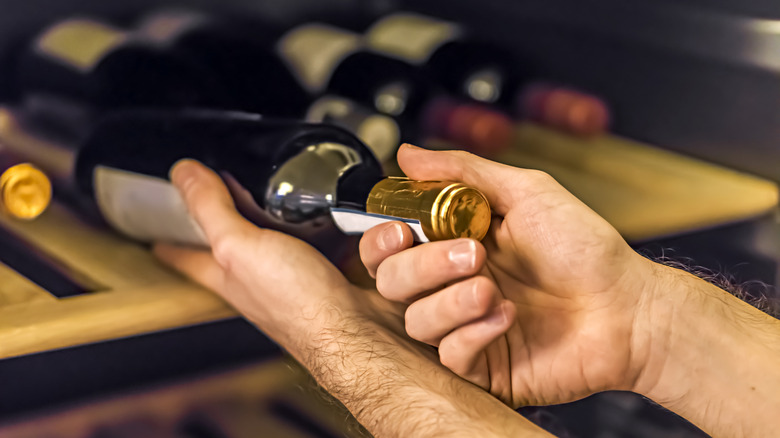 Man removing a bottle of wine from storage