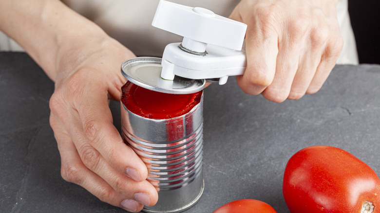 person opening can of tomatoes
