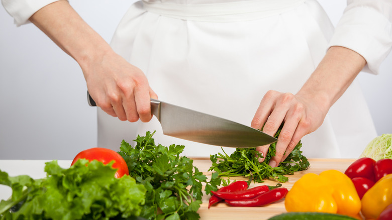 cook slicing herbs with chefs knife