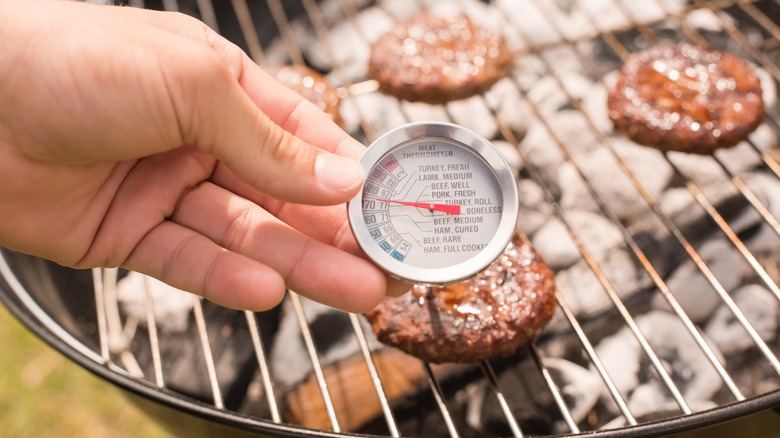 meat thermometer and burgers on grill