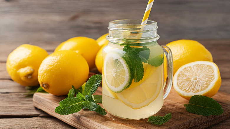 A mason jar full of lemonade, with lemons in the background