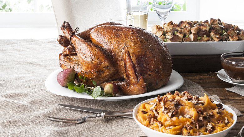 Stuffed roast turkey on platter surrounded by Thanksgiving side dishes