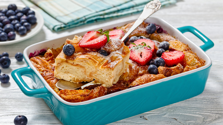 sweet croissant breakfast casserole in a blue baking dish with berries