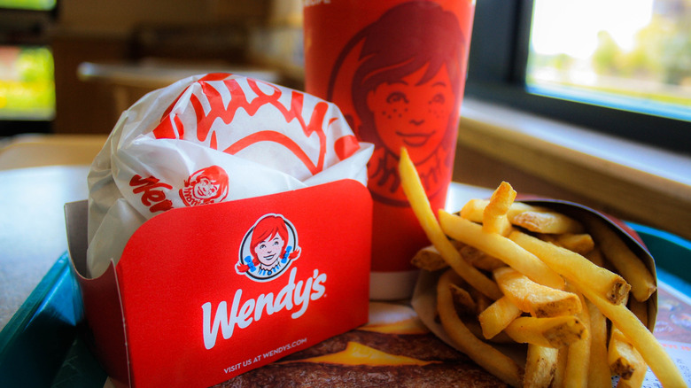 A Wendy's meal on a dine-in tray, with a neatly-wrapped burger, a drink in a red cup with the Wendy's logo on it, and a small order of French fries