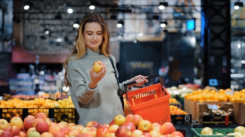 woman holding apple in store