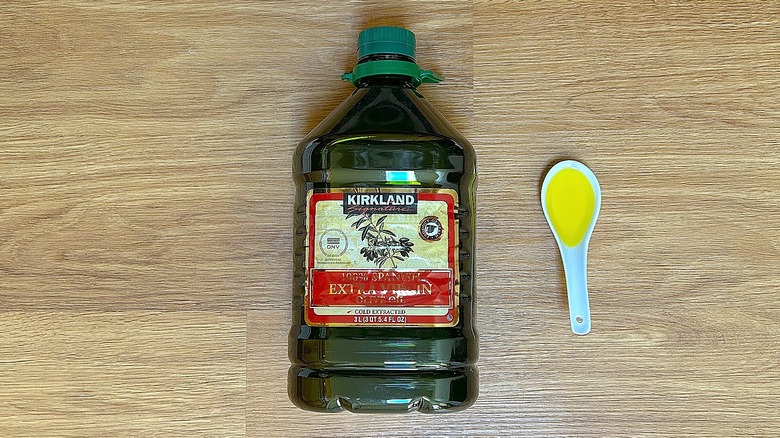 Bottle and spoonful of Kirkland Signature 100% Spanish Extra Virgin Olive Oil