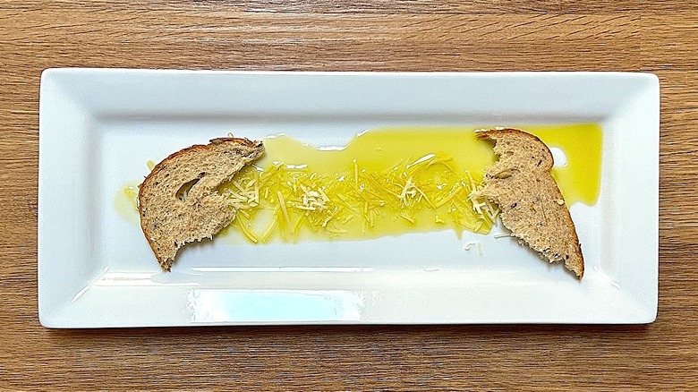 Rectangular white plate with olive oil, Parmesan cheese, and chunks of bread