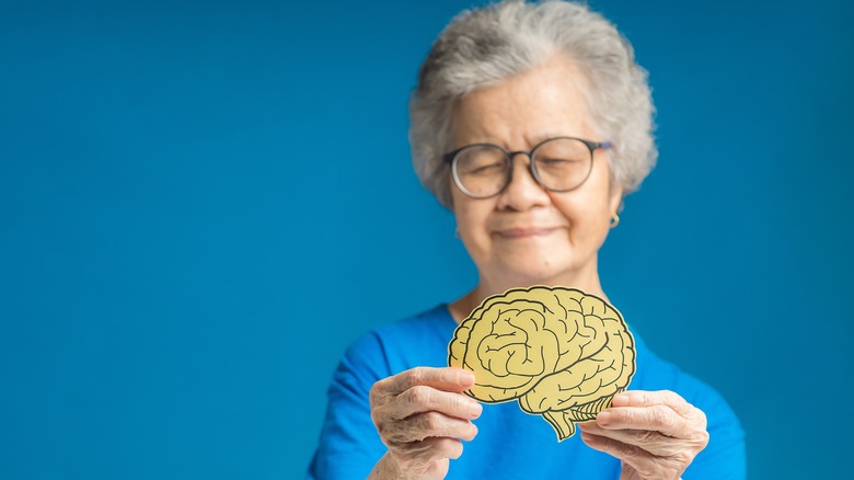 elderly woman holding image of brain