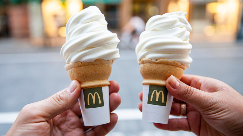 hands holding two McDonald's cones