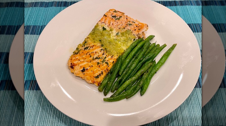 Costco Salmon Milano with herb butter, on white plate next to green beans